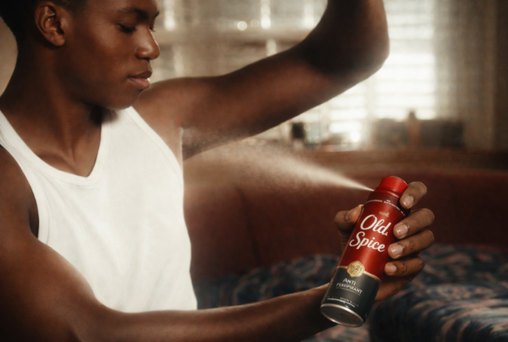 Young man using body spray